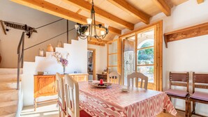 A dining area with a table set for four, wooden chairs, a chandelier, and a staircase leading to another room. - Charming Holiday Home Can Bonjesus with Mountain View, Wi-Fi, Garden & Terrace; Parking Available, Pets Allowed (Felanitx)