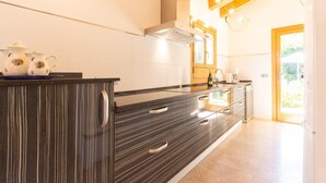 Una cucina moderna con un armadietto in legno scuro, zoccolo di piastrelle bianche e soffitto in legno.
