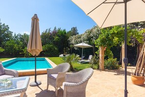 Un área junto a la piscina con tumbonas y una mesa.