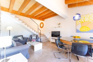 Una sala de estar moderna con una escalera, un comedor y un televisor.