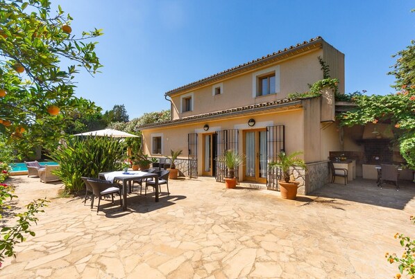 Una casa de dos plantas con un patio, muebles de exterior y una piscina.