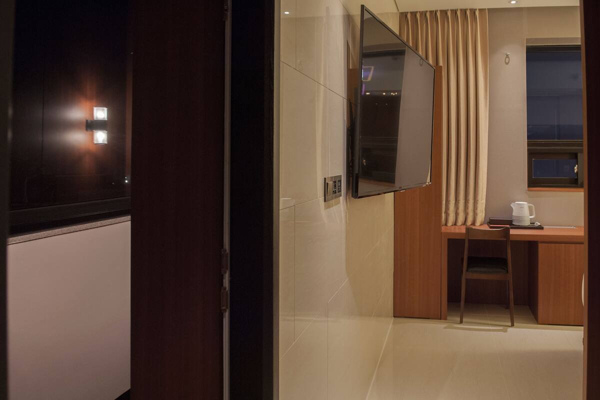 Habitación de hotel con escritorio, silla y un espejo grande.