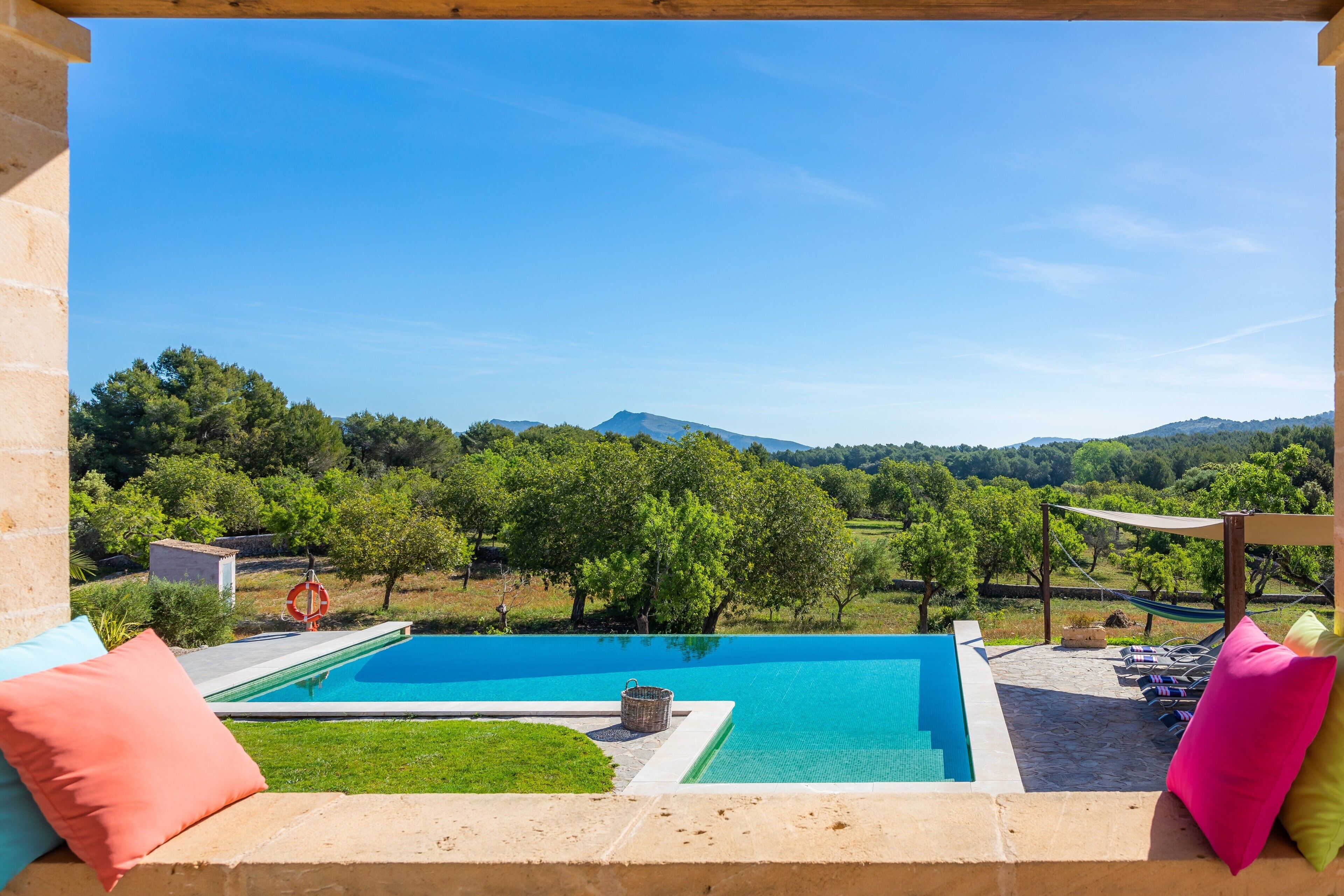 Une piscine avec vue sur un paysage montagneux, un hamac et un petit abri de jardin.