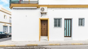 A white building with a wooden door, a window with bars, and a balcony with a railing. - Holiday Apartment "Estudio Lila" with Wi-Fi and Air Conditioning (Conil de la frontera)