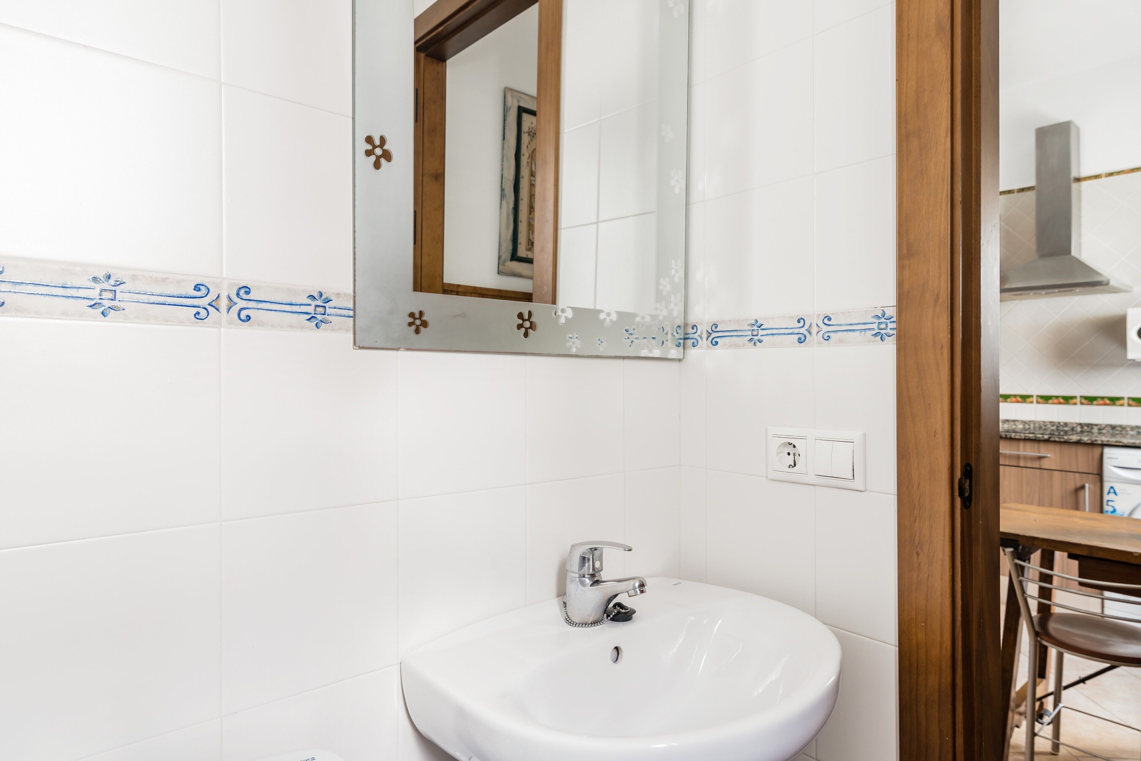 A bathroom with a white sink, a mirror, and a tiled backsplash.