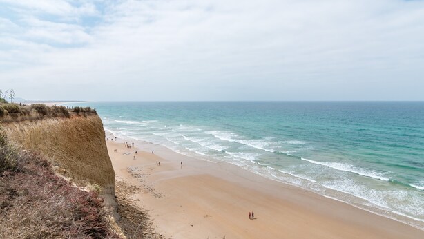 A beach with a cliff, ocean, and people walking. - Holiday Apartment "Estudio Lila" with Wi-Fi and Air Conditioning (Conil de la frontera)