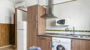 A compact kitchen with a built-in microwave, a washing machine, and a refrigerator. - Holiday Apartment "Estudio Lila" with Wi-Fi and Air Conditioning (Conil de la frontera)