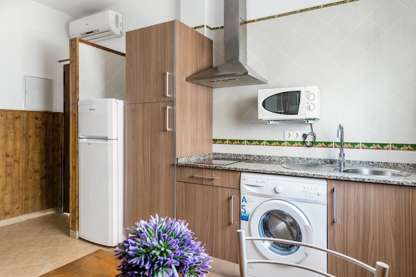 A compact kitchen with a built-in microwave, a washing machine, and a refrigerator.