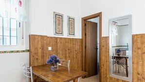 A dining area with a wooden table, chairs, and a potted plant. - Holiday Apartment "Estudio Lila" with Wi-Fi and Air Conditioning (Conil de la frontera)