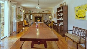 Un vaste espace dédié à la salle à manger, avec une longue table en bois, des bancs et une cheminée.