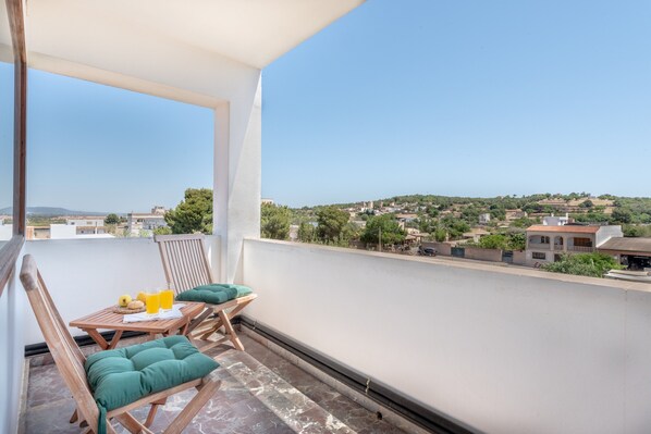 A balcony with a table, chairs, and a view of a town.