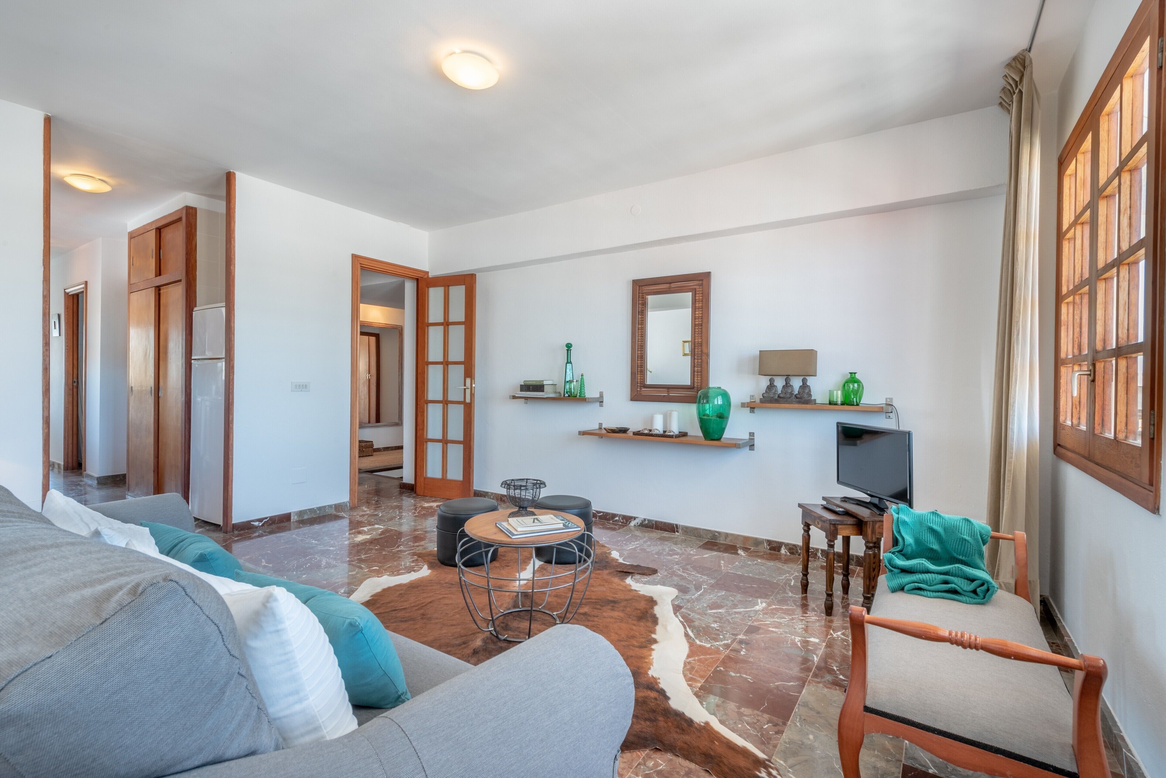 Una sala de estar moderna con un sofá, una mesa de centro, una silla y un televisor.