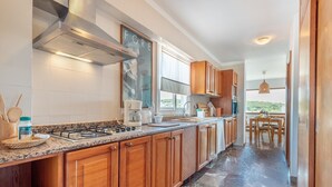 A modern kitchen with wooden cabinets, a gas stove, and a large window. - Modern Apartment with Balconies & Wi-Fi; Pets Allowed, Parking Available (Felanitx)