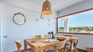 A dining area with a wooden table, chairs, a mirror, and a view of the countryside. - Modern Apartment with Balconies & Wi-Fi; Pets Allowed, Parking Available (Felanitx)