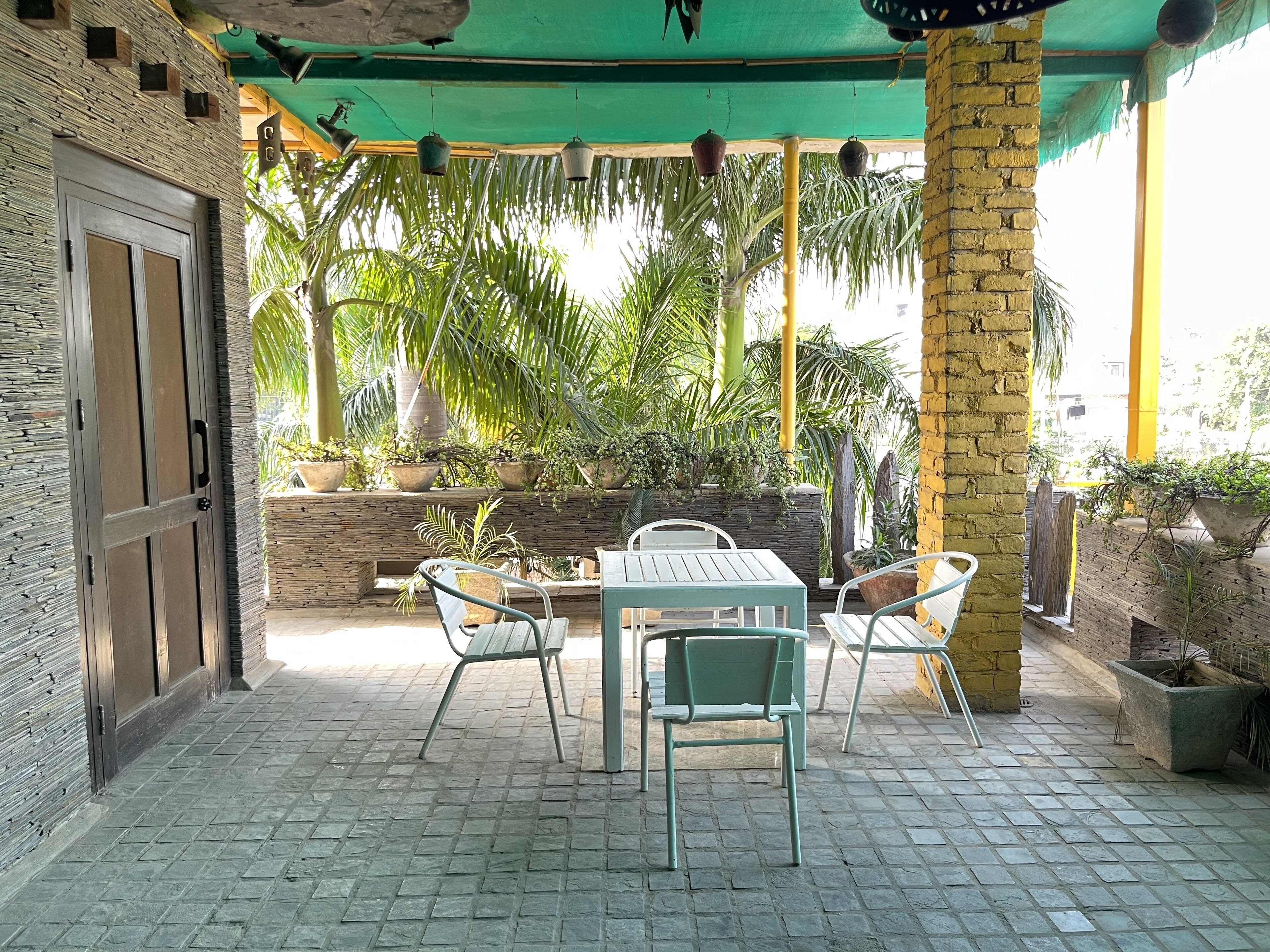 An outdoor patio with a table and chairs, surrounded by potted plants and a brick wall.