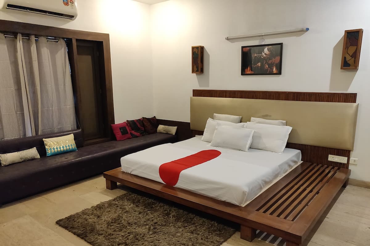 A bedroom with a bed, a sofa, a rug, and a wall-mounted picture.