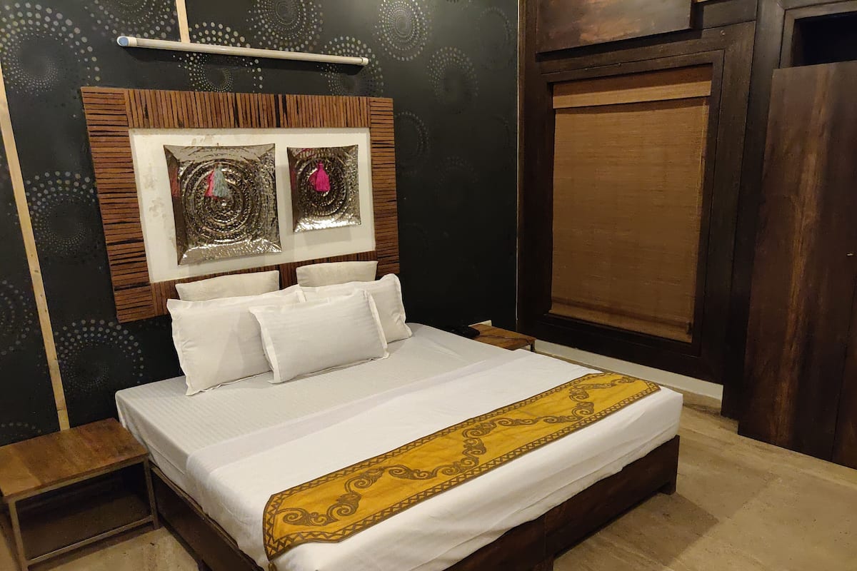 A neatly made bed with white linens and a decorative yellow and brown bedspread.