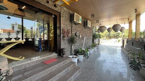 A hotel entrance with a stone facade, a Pepsi sign, and a staircase leading to the entrance. - Aakritii Hotels (Gurugram)