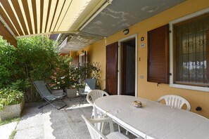 A patio with a table and chairs, a wooden door, and a window with a number.