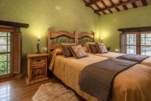 A bedroom with two beds, wooden headboards, and a nightstand with a lamp.