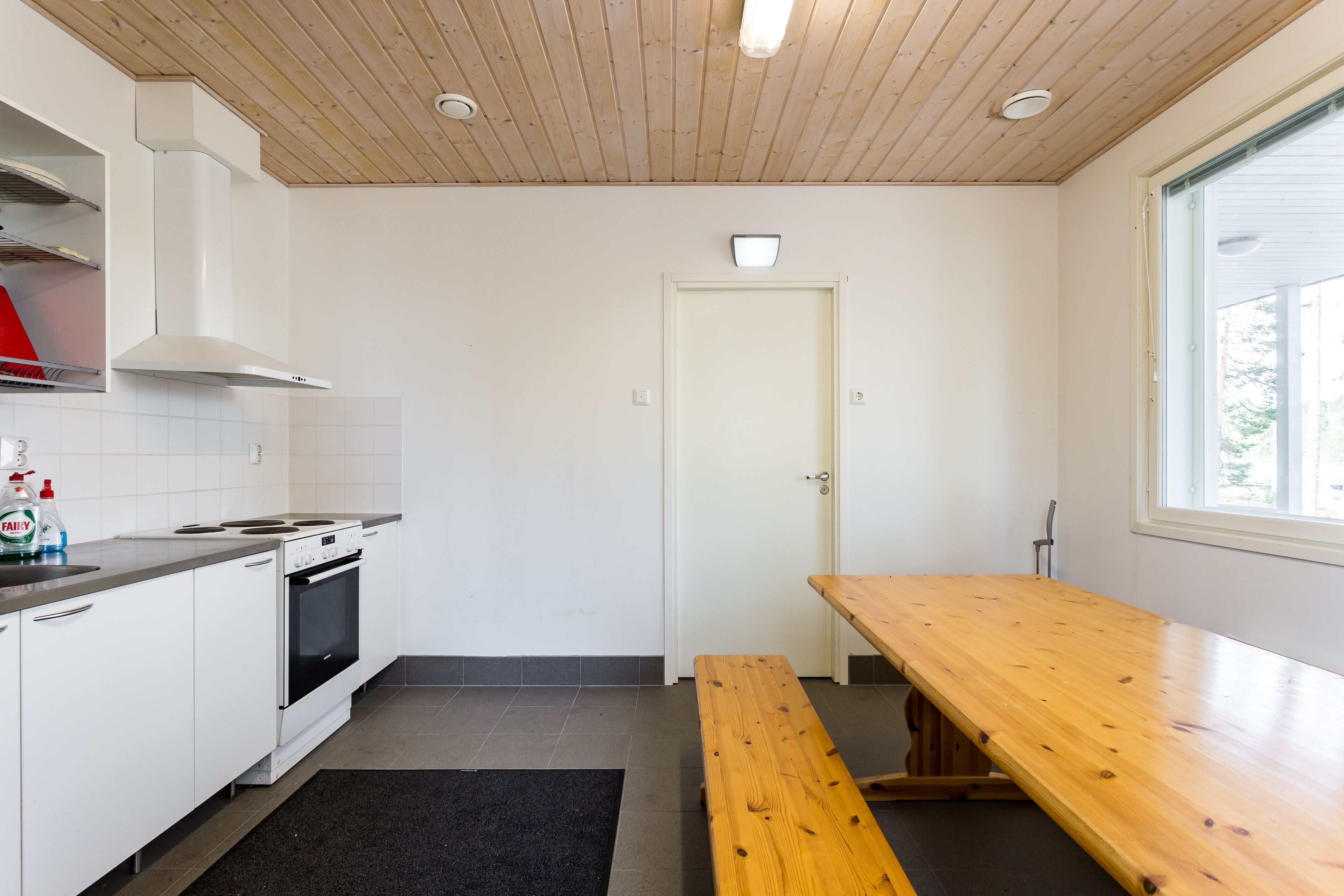 Een moderne keuken met witte kasten, een fornuis en een houten bankje.