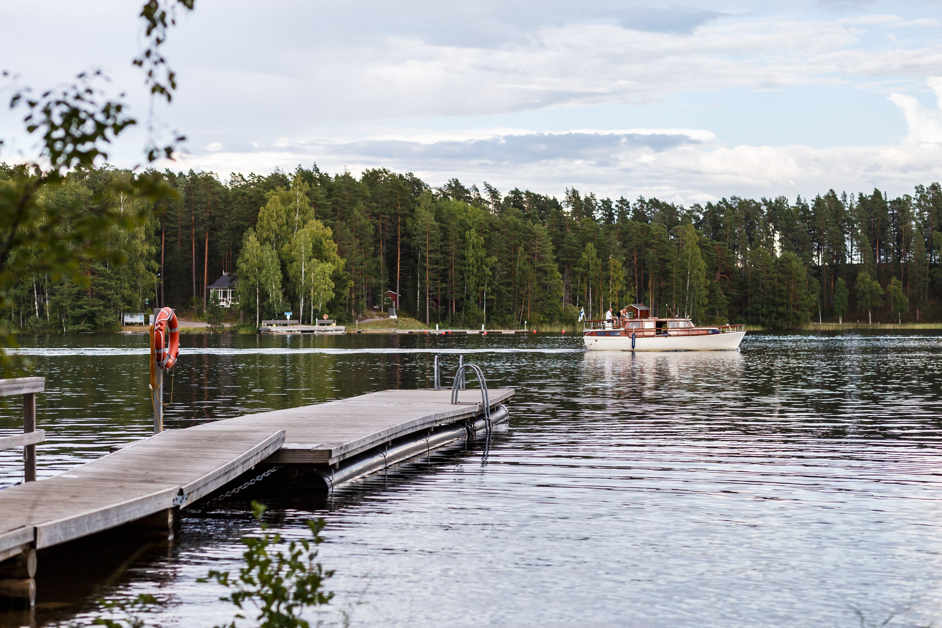 A calm lake with a wooden dock extending into the water, surrounded by dense forest.