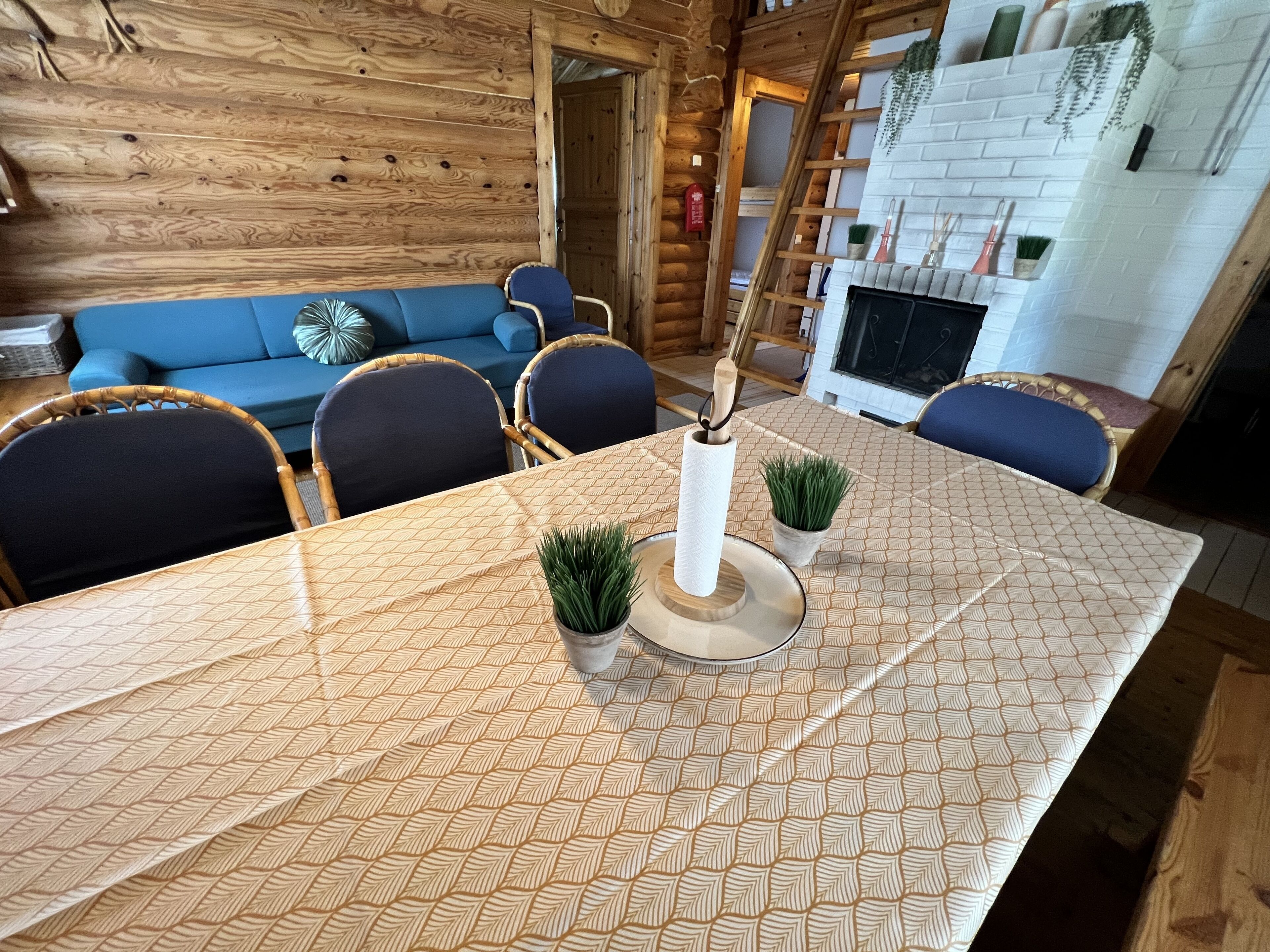 A wooden interior with a dining table, chairs, a sofa, and a fireplace.