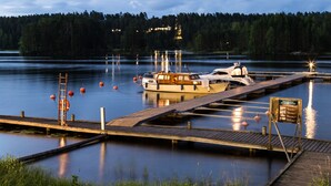 A calm lake with a dock, a boat, and a signboard. - Punkaharju Resort (Savonlinna)