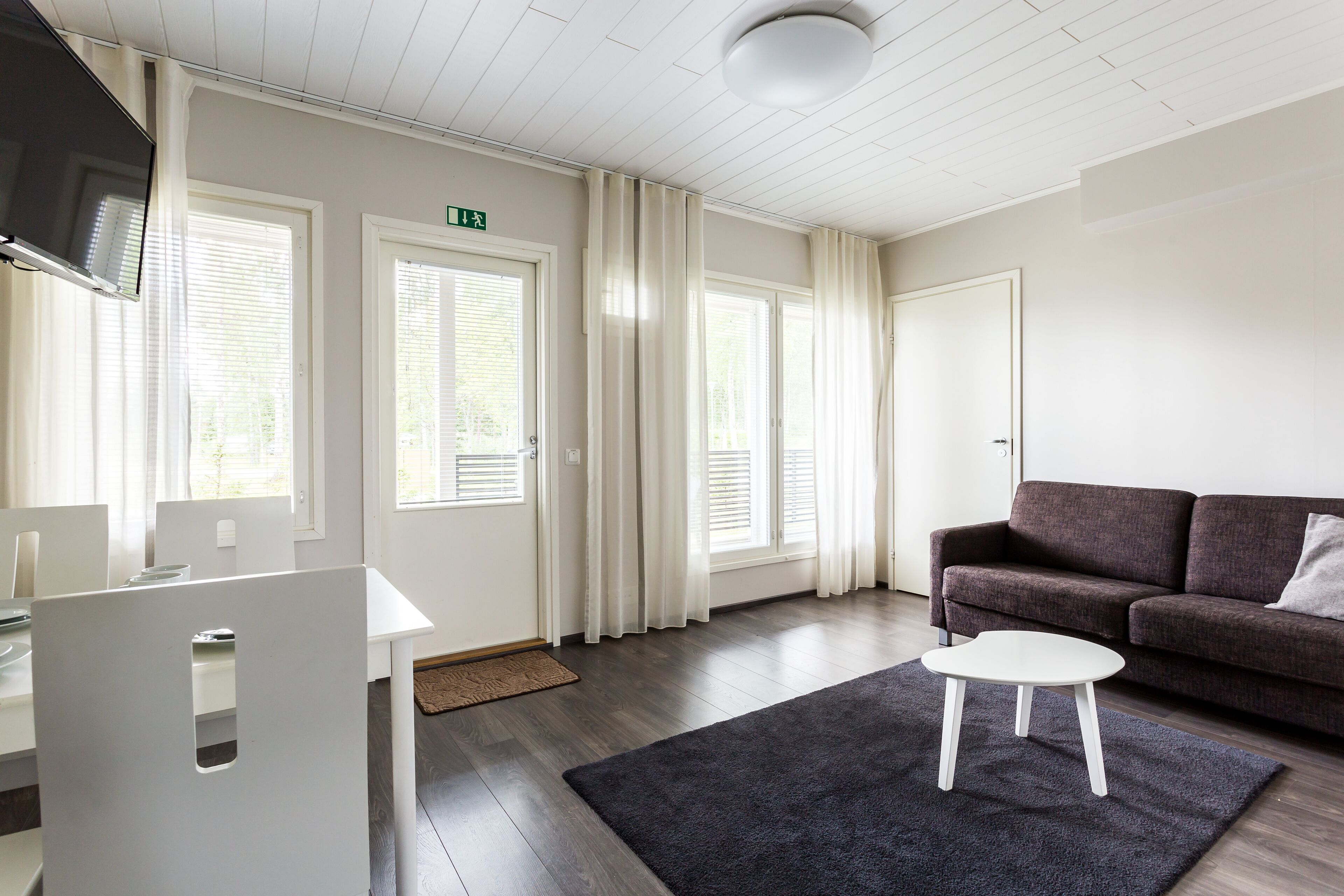 Un salon moderne avec un canapé gris foncé, une table basse blanche et un téléviseur à écran plat fixé au mur.