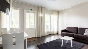 Un salon moderne avec un canapé gris foncé, une table basse blanche et un téléviseur à écran plat fixé au mur.