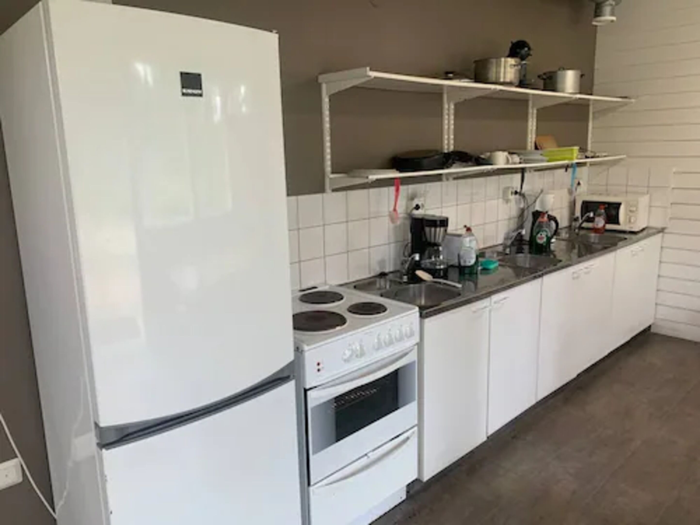 Una cocina con armarios blancos, estufa, horno y microondas.