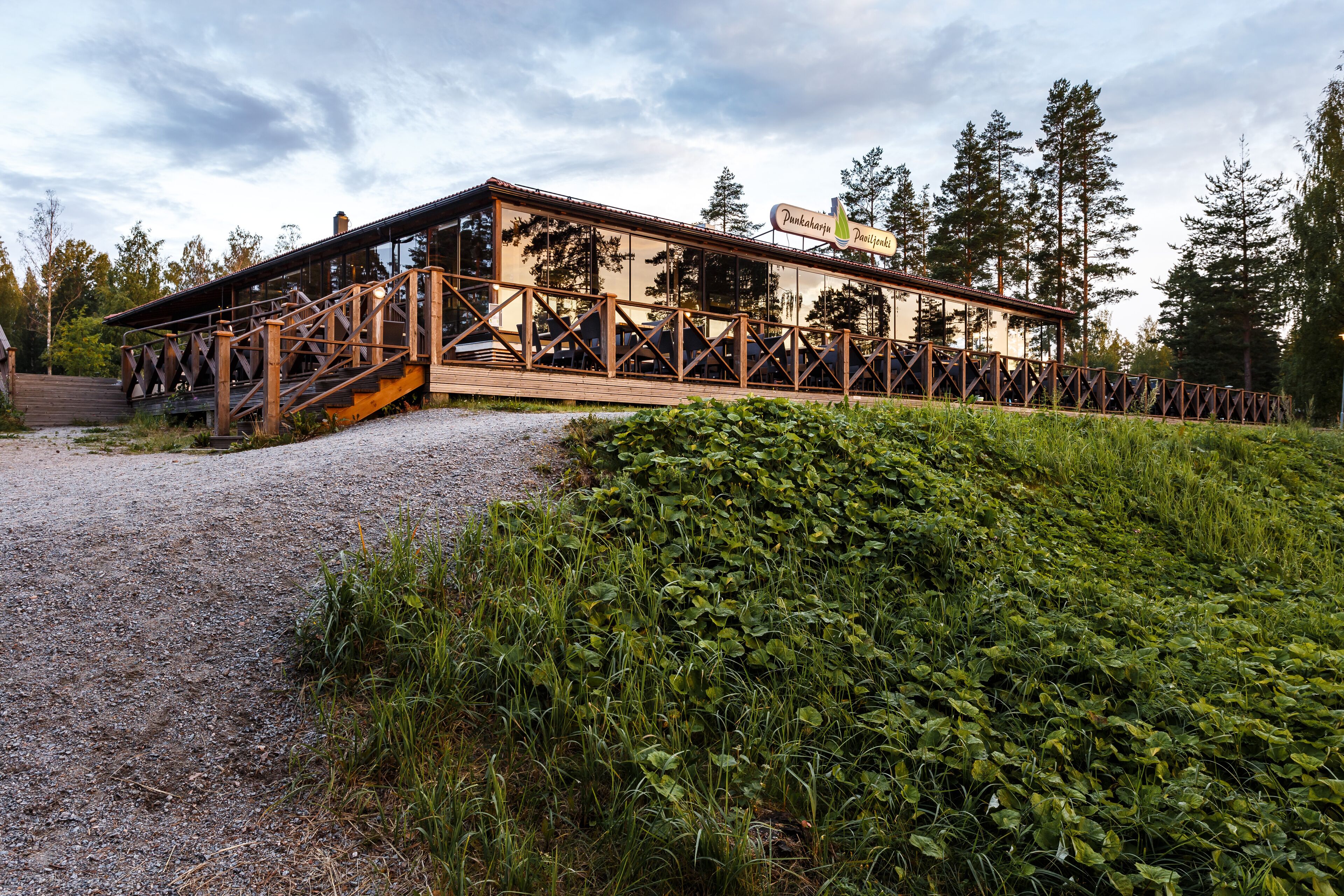 Ein Holzhaus mit einer überdachten Terrasse, umgeben von Grünpflanzen und Bäumen.
