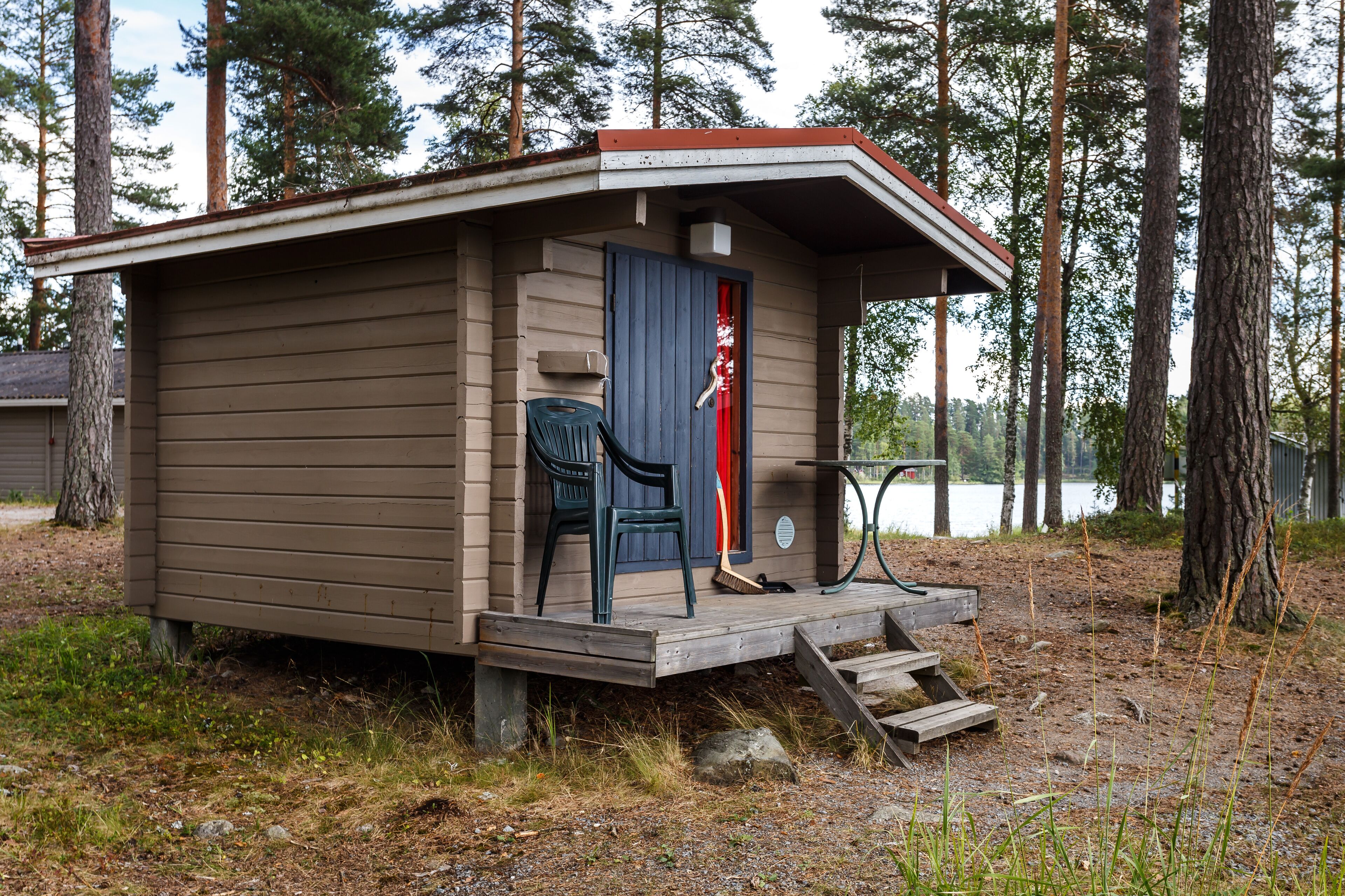 A small cabin with a wooden deck, a door, and a bench.