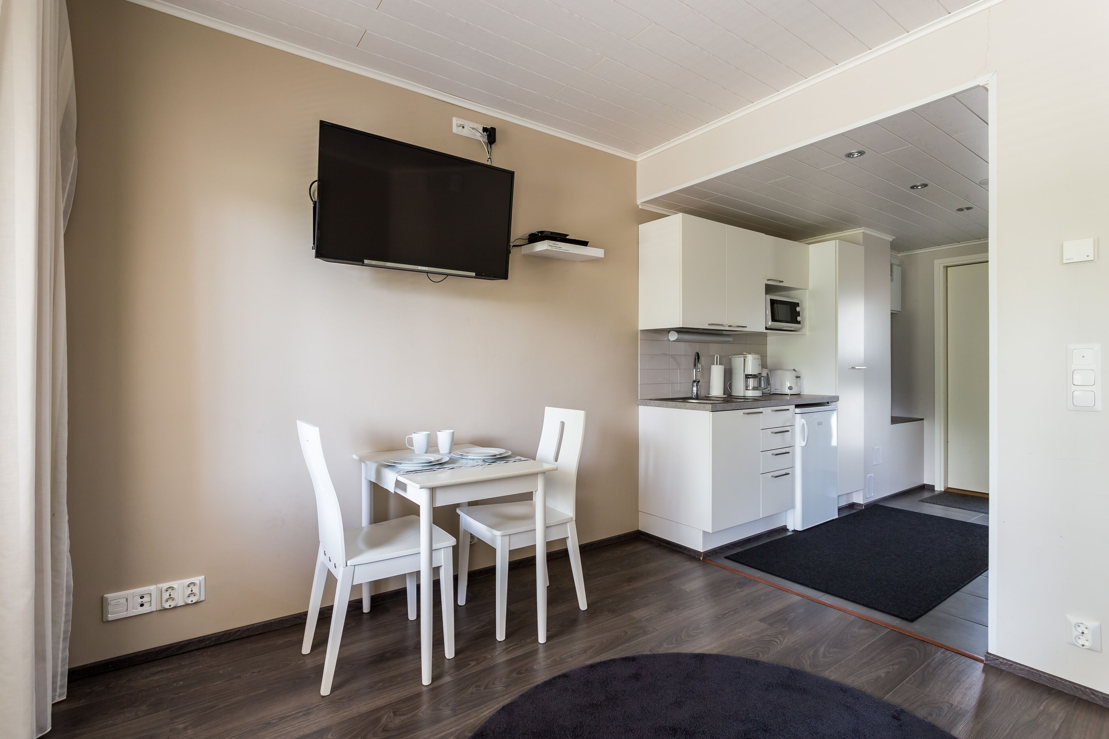A modern kitchen with white cabinets, a microwave, and a black countertop.