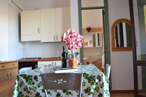 A kitchen with white cabinets, a table with a green and white tablecloth, and a chair with a floral design.