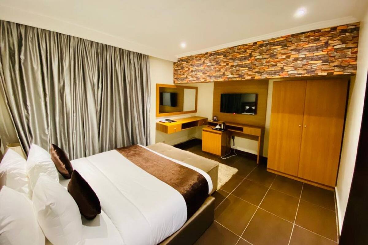 Een hotelkamer met een bed, een bureau, een televisie en een kledingkast.