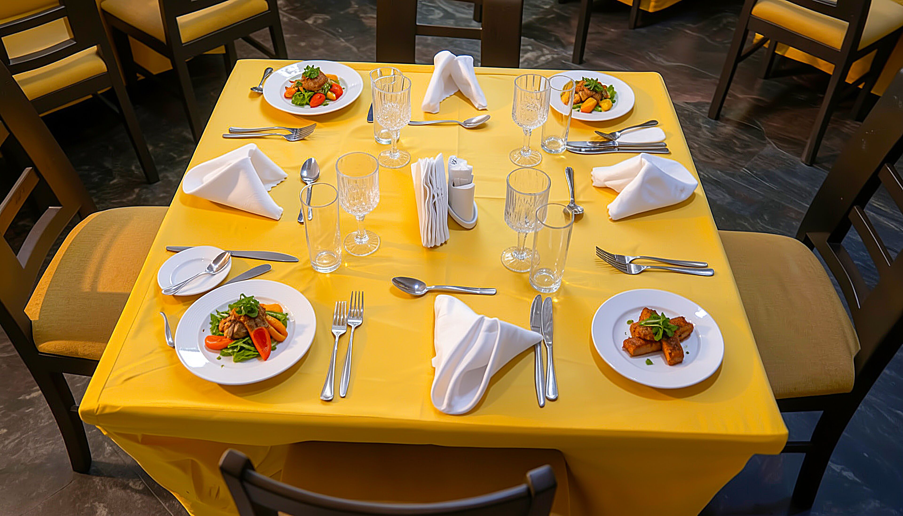 Een eettafel gedekt met borden, bestek en glazen, omringd door stoelen.