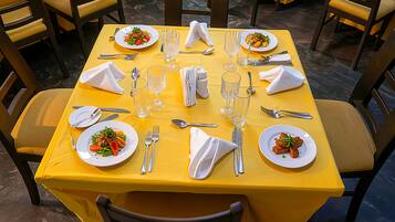 A dining table set with plates, cutlery, and glasses, surrounded by chairs.
