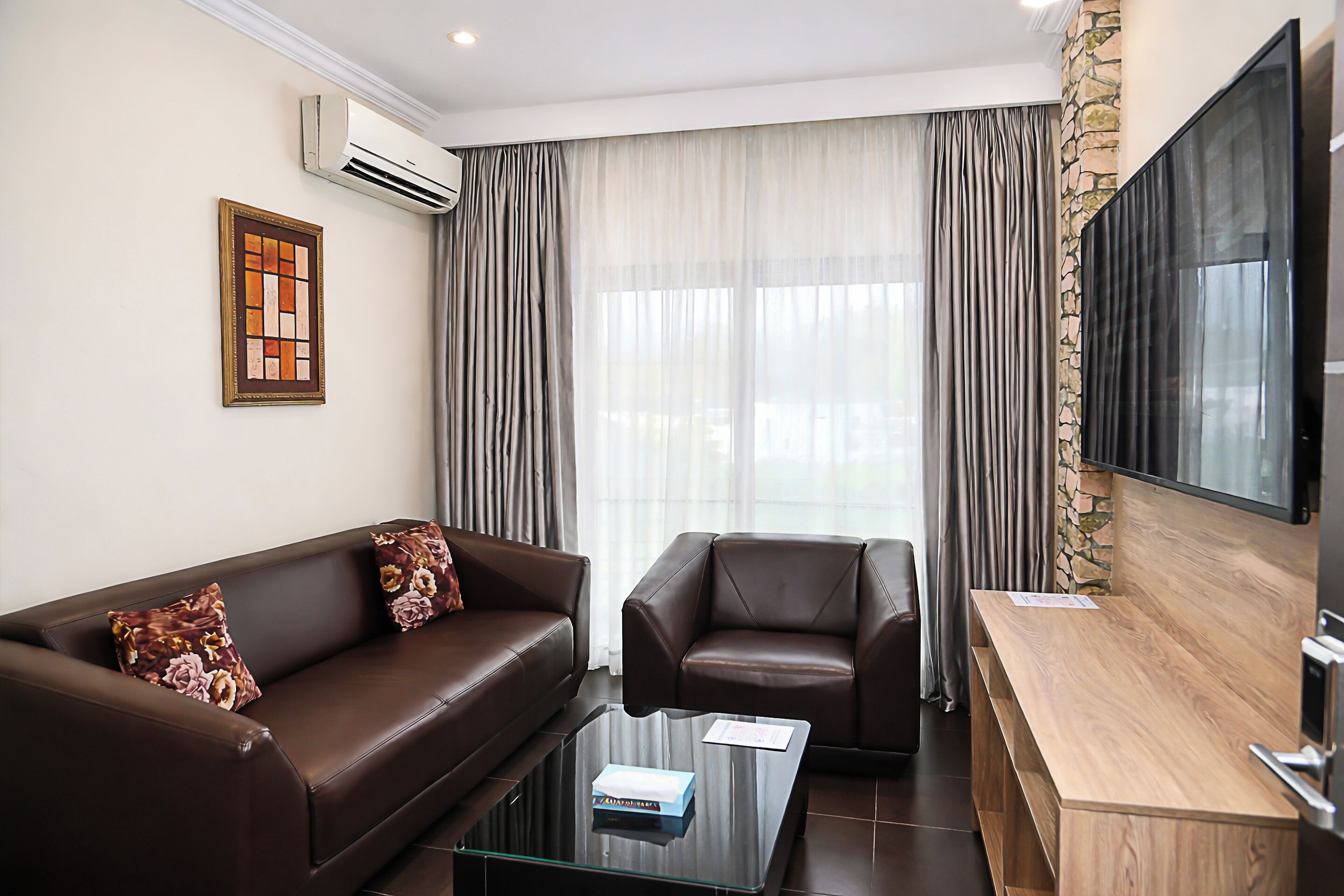 A modern living room with a sofa, armchair, coffee table, and a flat-screen TV.