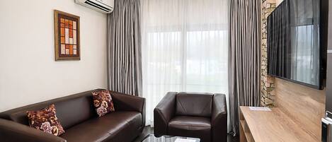 A modern living room with a sofa, armchair, coffee table, and a flat-screen TV.