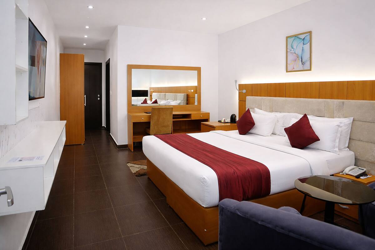 Een hotelkamer met een bed, een bureau, een stoel, een kleine tafel, een spiegel en een telefoon.