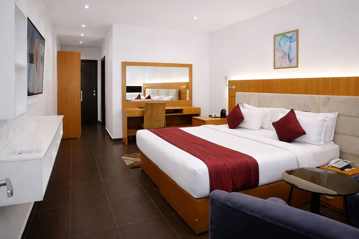Une chambre d’hôtel équipée d’un lit, d’un bureau, d’une chaise, d’une petite table, d’un miroir et d’un téléphone.