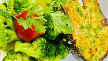 A plate with grilled chicken, broccoli, and a cherry tomato.