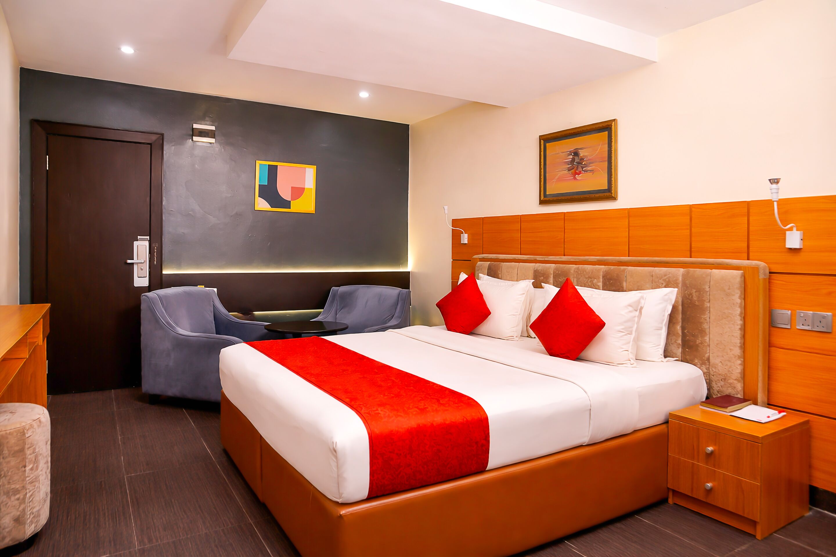 Hotelkamer met een groot bed, een bureau, een stoel, een nachtkastje en een aan de muur bevestigde televisie.