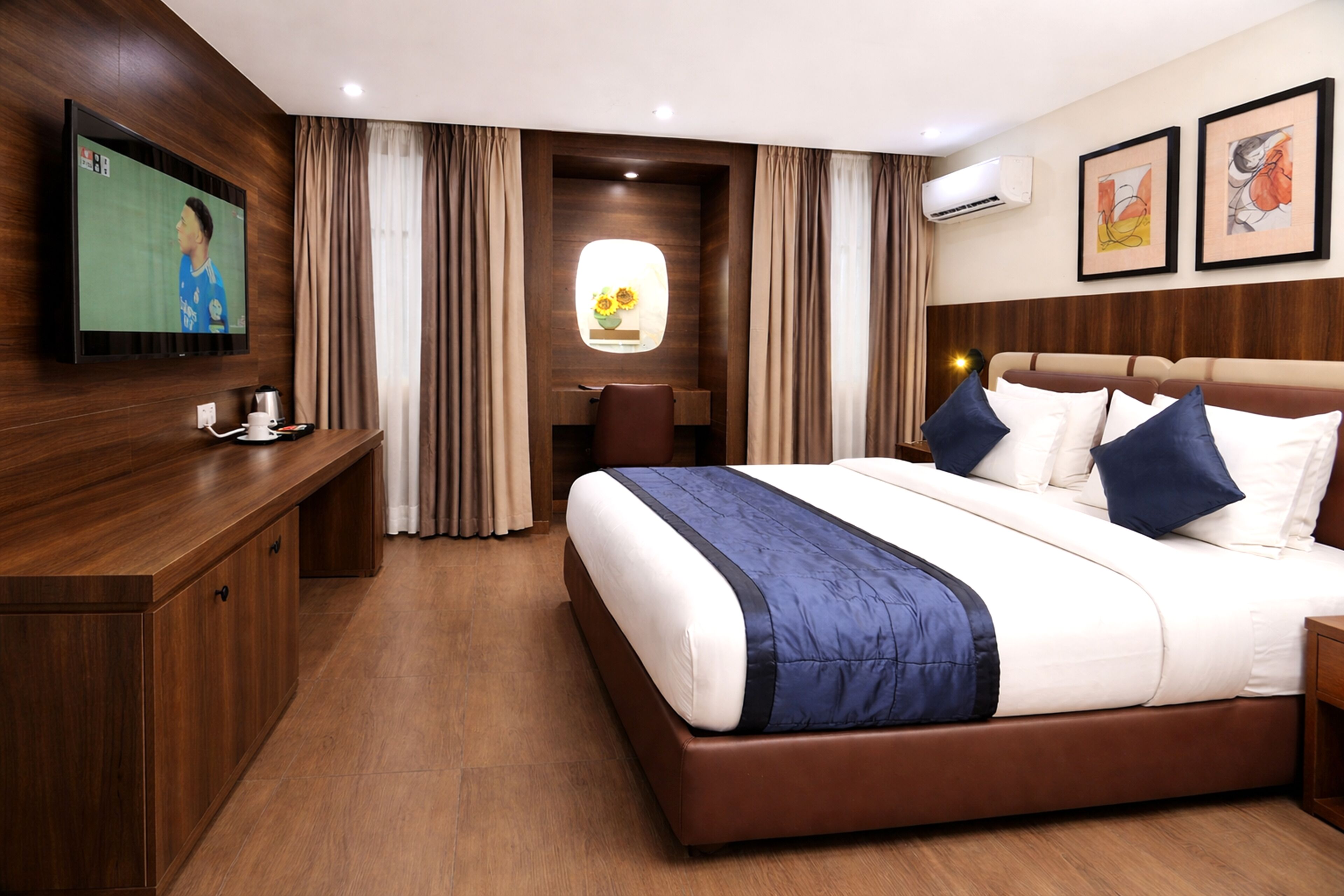 A hotel room with a large bed, a desk, a TV, and a window with curtains.