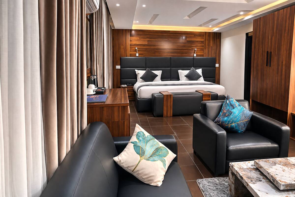 Een moderne hotelkamer met een groot bed, een slaapbank, een bijzettafeltje en een bureau.