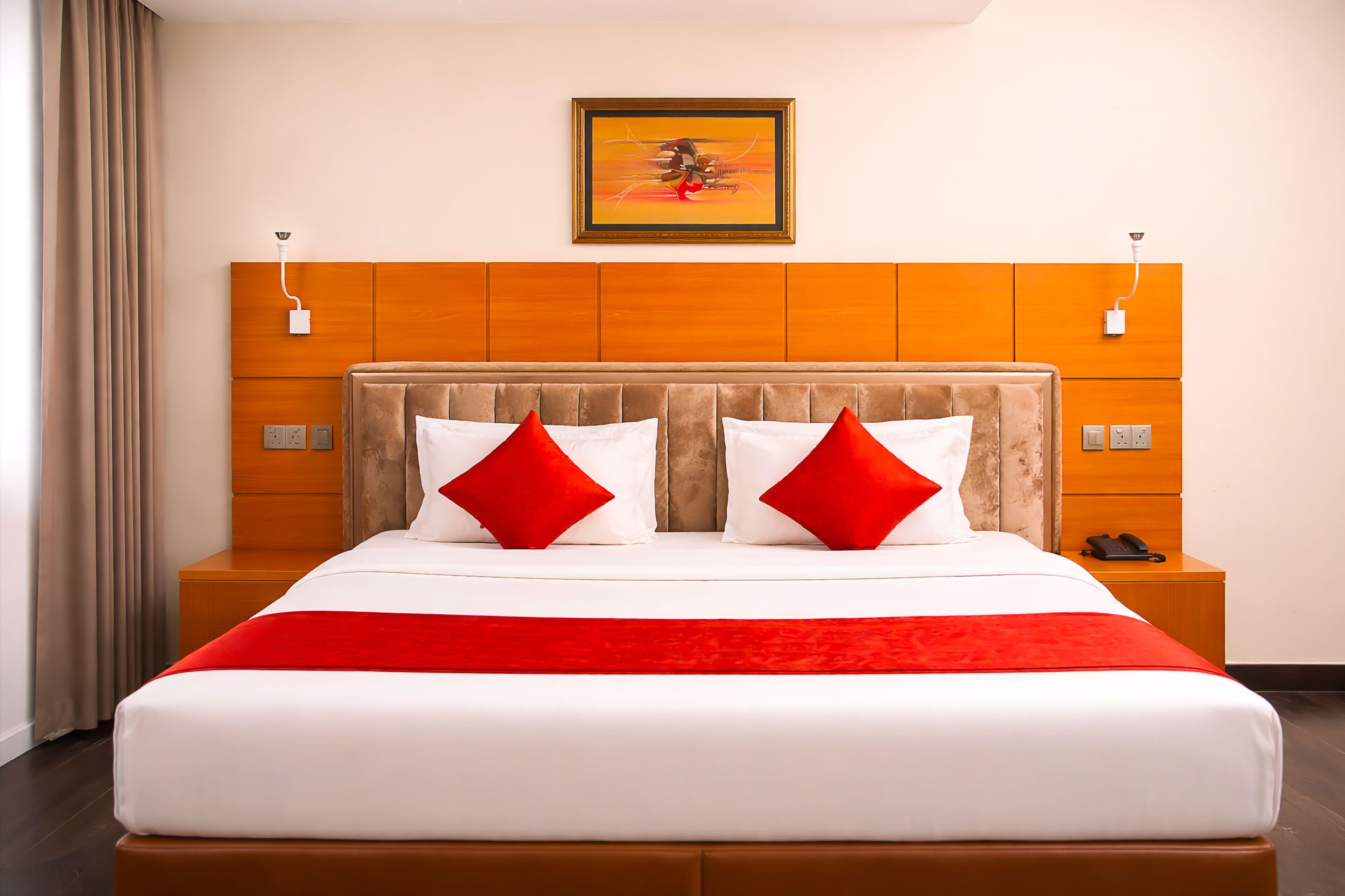 Ein Hotelzimmer mit einem großen Bett, einem hölzernen Kopfteil, einer roten Decke und einem Bild an der Wand.