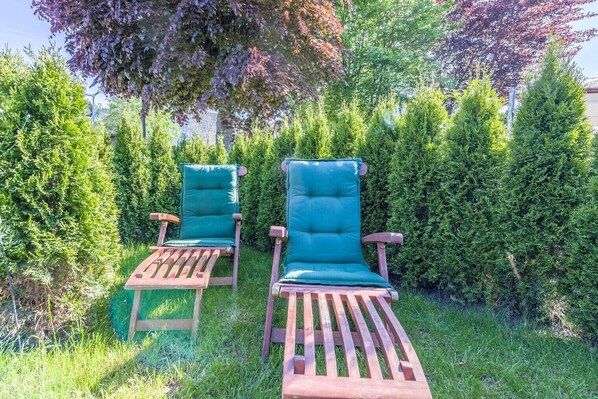 Dos sillones de madera con cojines verdes en un jardín.