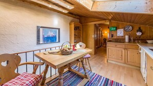Un interior de madera acogedor, con comedor, cocina y vistas de la ciudad a través de un tragaluz.