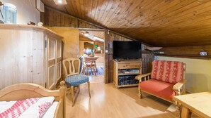 Un interior de madera con una cama, un televisor, una silla y un comedor.